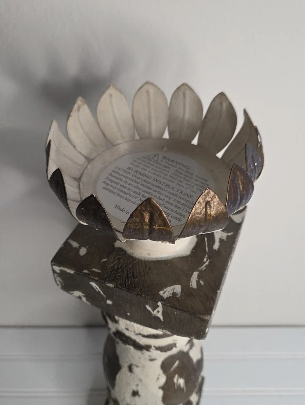 white and gold candlestick features a distressed finish and a lotus-shaped top